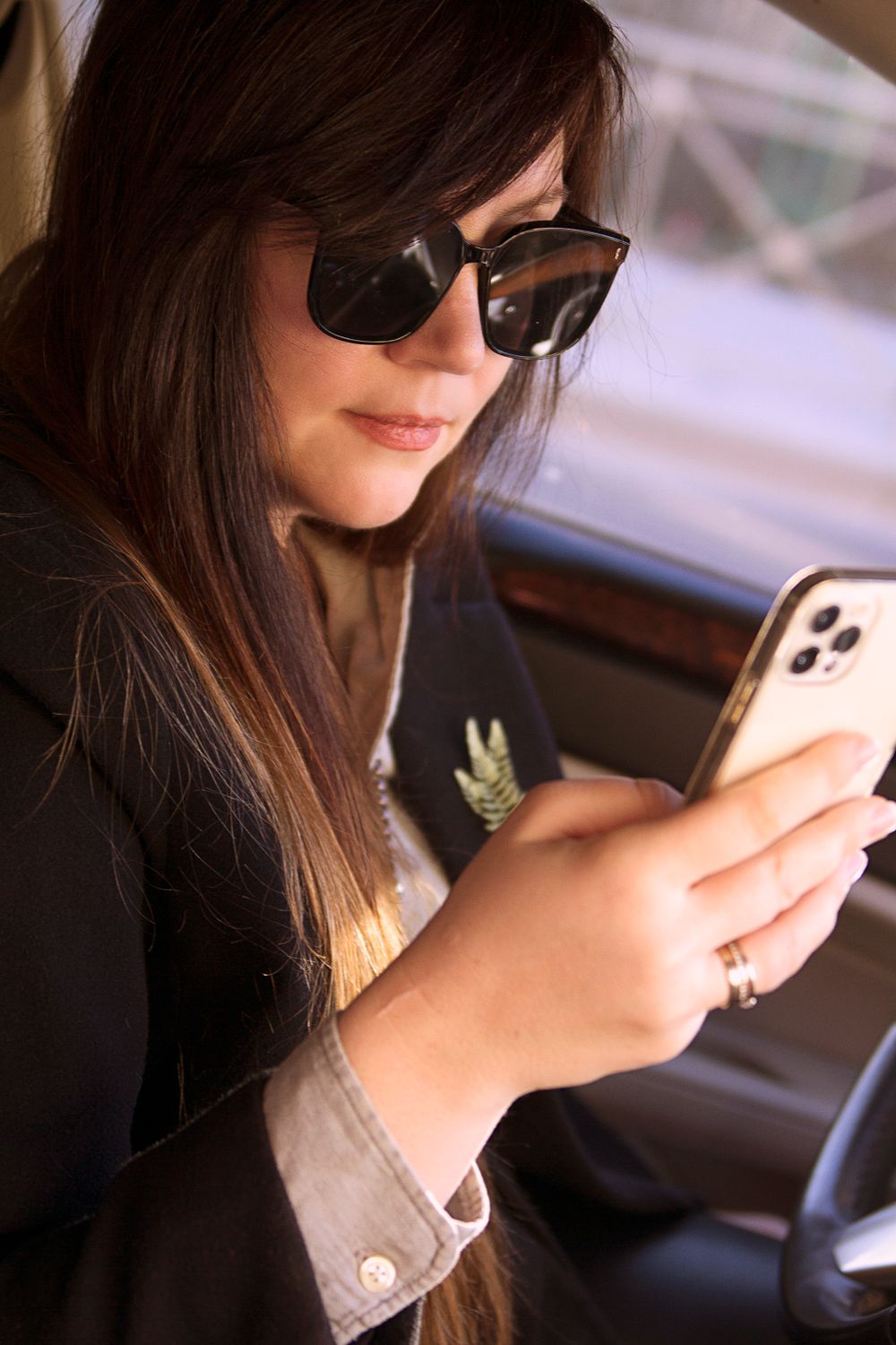 Mujer sentada en su auto mirando el celular